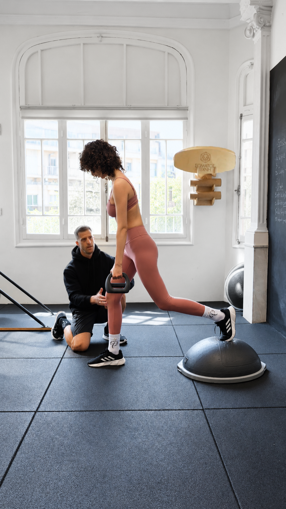 Personal trainer guiding a balance exercise with a kettlebell and BOSU