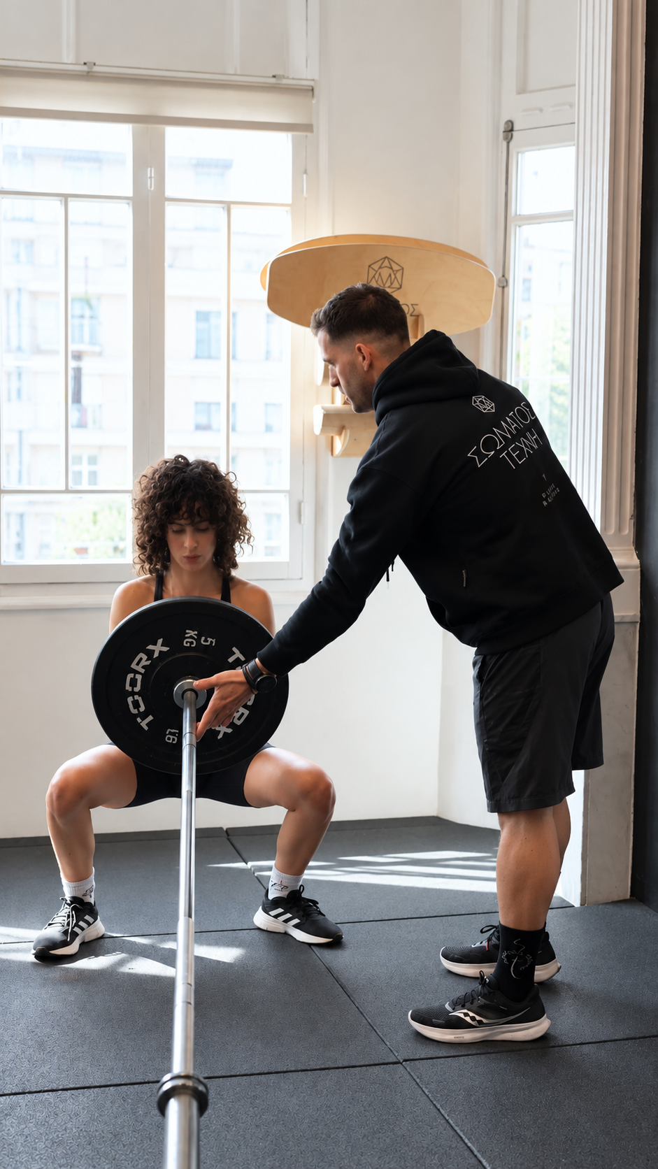 Personal trainer guiding a landmine squat at Somatos Techni